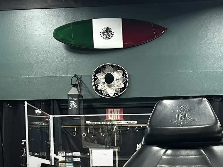 A surfboard painted in the colours of the Mexican flag, mounted high on the wall